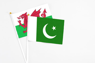 Pakistan and Wales stick flags on white background. High quality fabric, miniature national flag. Peaceful global concept.White floor for copy space.