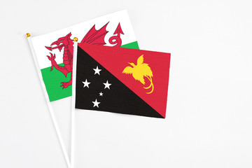 Papua New Guinea and Wales stick flags on white background. High quality fabric, miniature national flag. Peaceful global concept.White floor for copy space.