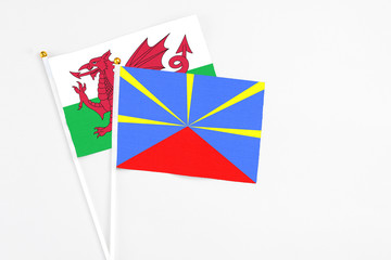 Reunion and Wales stick flags on white background. High quality fabric, miniature national flag. Peaceful global concept.White floor for copy space.