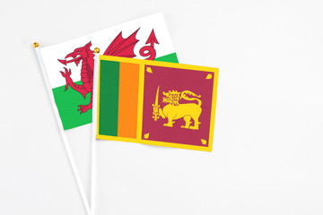 Sri Lanka and Wales stick flags on white background. High quality fabric, miniature national flag. Peaceful global concept.White floor for copy space.