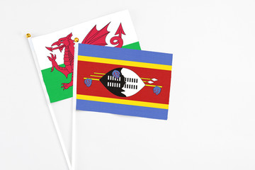 Swaziland and Wales stick flags on white background. High quality fabric, miniature national flag. Peaceful global concept.White floor for copy space.