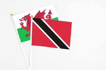Trinidad And Tobago and Wales stick flags on white background. High quality fabric, miniature national flag. Peaceful global concept.White floor for copy space.
