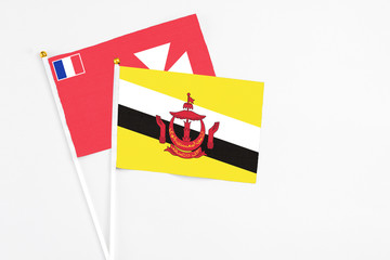Brunei and Wallis And Futuna stick flags on white background. High quality fabric, miniature national flag. Peaceful global concept.White floor for copy space.
