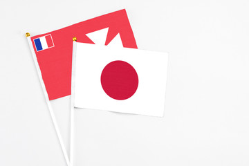 Japan and Wallis And Futuna stick flags on white background. High quality fabric, miniature national flag. Peaceful global concept.White floor for copy space.