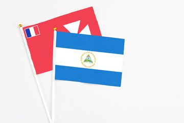 Nicaragua and Wallis And Futuna stick flags on white background. High quality fabric, miniature national flag. Peaceful global concept.White floor for copy space.