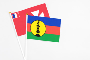 New Caledonia and Wallis And Futuna stick flags on white background. High quality fabric, miniature national flag. Peaceful global concept.White floor for copy space.