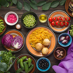 Food Composition. Organic food, vegetables and cereals in multi-colored clay bowls on a wooden table. View overhead. The concept of vegetarian food.