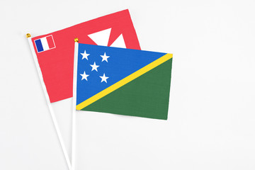 Solomon Islands and Wallis And Futuna stick flags on white background. High quality fabric, miniature national flag. Peaceful global concept.White floor for copy space.