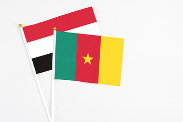 Fototapeta premium Cameroon and Yemen stick flags on white background. High quality fabric, miniature national flag. Peaceful global concept.White floor for copy space.