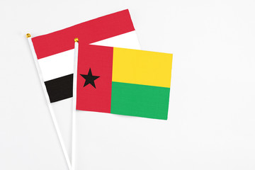 Guinea Bissau and Yemen stick flags on white background. High quality fabric, miniature national flag. Peaceful global concept.White floor for copy space.