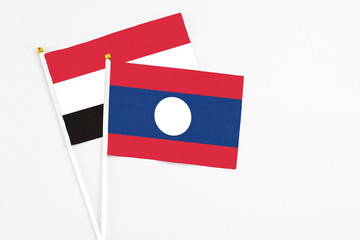 Laos and Yemen stick flags on white background. High quality fabric, miniature national flag. Peaceful global concept.White floor for copy space.