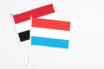 Luxembourg and Yemen stick flags on white background. High quality fabric, miniature national flag. Peaceful global concept.White floor for copy space.