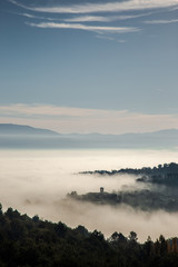 Surreal view of of a little town in Umbria (Italy) almost completely hidden by fog