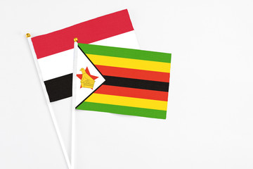 Zimbabwe and Yemen stick flags on white background. High quality fabric, miniature national flag. Peaceful global concept.White floor for copy space.