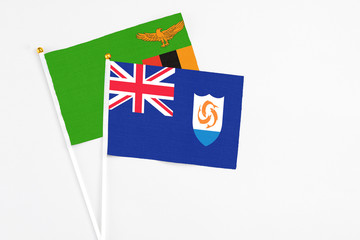 Fototapeta premium Anguilla and Zambia stick flags on white background. High quality fabric, miniature national flag. Peaceful global concept.White floor for copy space.