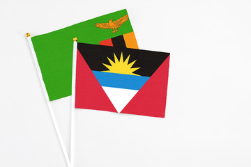 Antigua and Barbuda and Zambia stick flags on white background. High quality fabric, miniature national flag. Peaceful global concept.White floor for copy space.