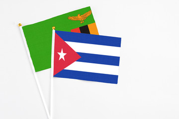 Obraz premium Cuba and Zambia stick flags on white background. High quality fabric, miniature national flag. Peaceful global concept.White floor for copy space.