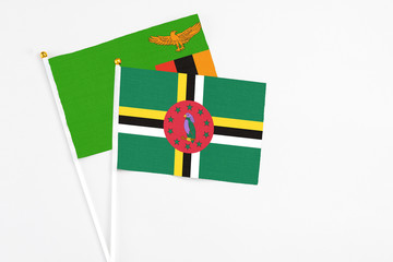 Fototapeta premium Dominica and Zambia stick flags on white background. High quality fabric, miniature national flag. Peaceful global concept.White floor for copy space.