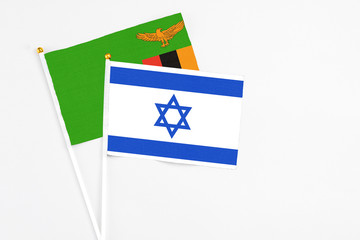 Israel and Zambia stick flags on white background. High quality fabric, miniature national flag. Peaceful global concept.White floor for copy space.