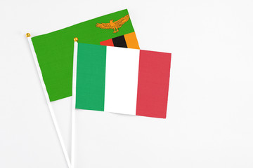 Italy and Zambia stick flags on white background. High quality fabric, miniature national flag. Peaceful global concept.White floor for copy space.