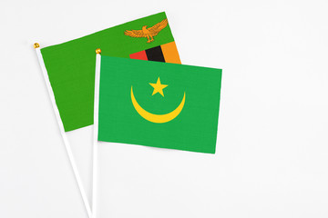 Mauritania and Zambia stick flags on white background. High quality fabric, miniature national flag. Peaceful global concept.White floor for copy space.