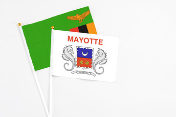 Mayotte and Zambia stick flags on white background. High quality fabric, miniature national flag. Peaceful global concept.White floor for copy space.