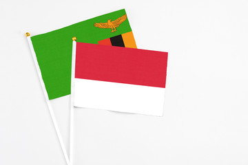 Monaco and Zambia stick flags on white background. High quality fabric, miniature national flag. Peaceful global concept.White floor for copy space.