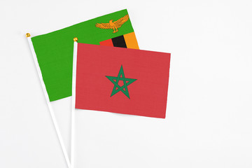 Morocco and Zambia stick flags on white background. High quality fabric, miniature national flag. Peaceful global concept.White floor for copy space.