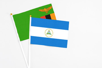 Nicaragua and Zambia stick flags on white background. High quality fabric, miniature national flag. Peaceful global concept.White floor for copy space.