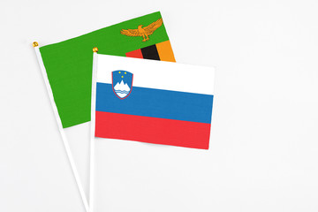 Slovenia and Zambia stick flags on white background. High quality fabric, miniature national flag. Peaceful global concept.White floor for copy space.