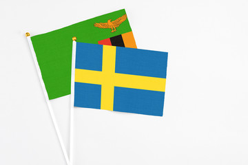 Sweden and Zambia stick flags on white background. High quality fabric, miniature national flag. Peaceful global concept.White floor for copy space.