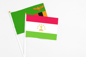 Tajikistan and Zambia stick flags on white background. High quality fabric, miniature national flag. Peaceful global concept.White floor for copy space.