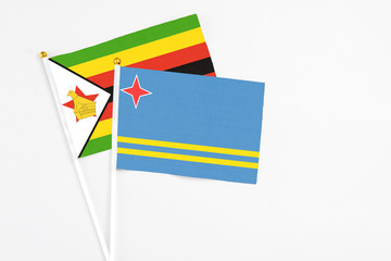 Aruba and Zimbabwe stick flags on white background. High quality fabric, miniature national flag. Peaceful global concept.White floor for copy space.