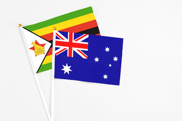 Fototapeta premium Australia and Zimbabwe stick flags on white background. High quality fabric, miniature national flag. Peaceful global concept.White floor for copy space.