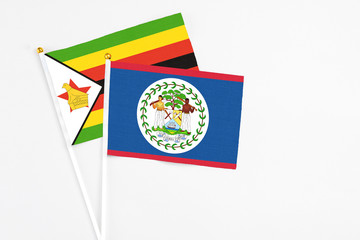 Belize and Zimbabwe stick flags on white background. High quality fabric, miniature national flag. Peaceful global concept.White floor for copy space.
