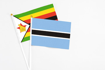 Botswana and Zimbabwe stick flags on white background. High quality fabric, miniature national flag. Peaceful global concept.White floor for copy space.