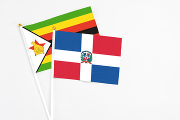 Dominican Republic and Zimbabwe stick flags on white background. High quality fabric, miniature national flag. Peaceful global concept.White floor for copy space.