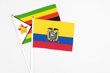 Ecuador and Zimbabwe stick flags on white background. High quality fabric, miniature national flag. Peaceful global concept.White floor for copy space.