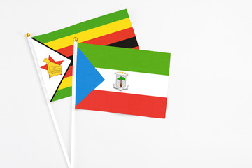 Equatorial Guinea and Zimbabwe stick flags on white background. High quality fabric, miniature national flag. Peaceful global concept.White floor for copy space.