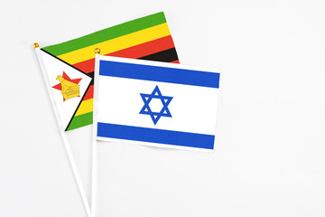 Israel and Zimbabwe stick flags on white background. High quality fabric, miniature national flag. Peaceful global concept.White floor for copy space.