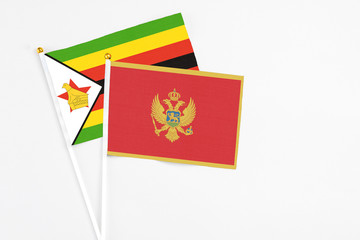 Montenegro and Zimbabwe stick flags on white background. High quality fabric, miniature national flag. Peaceful global concept.White floor for copy space.