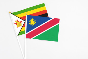 Namibia and Zimbabwe stick flags on white background. High quality fabric, miniature national flag. Peaceful global concept.White floor for copy space.