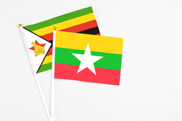 Myanmar and Zimbabwe stick flags on white background. High quality fabric, miniature national flag. Peaceful global concept.White floor for copy space.