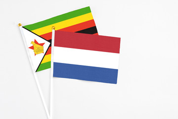 Netherlands and Zimbabwe stick flags on white background. High quality fabric, miniature national flag. Peaceful global concept.White floor for copy space.