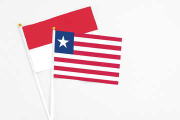 Liberia and Indonesia stick flags on white background. High quality fabric, miniature national flag. Peaceful global concept.White floor for copy space.