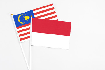 Indonesia and Malaysia stick flags on white background. High quality fabric, miniature national flag. Peaceful global concept.White floor for copy space.
