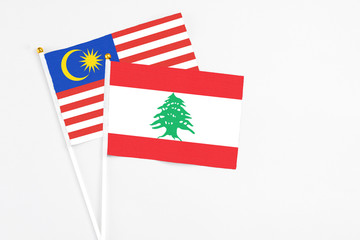 Lebanon and Malaysia stick flags on white background. High quality fabric, miniature national flag. Peaceful global concept.White floor for copy space.