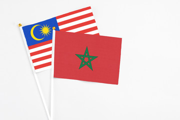 Morocco and Malaysia stick flags on white background. High quality fabric, miniature national flag. Peaceful global concept.White floor for copy space.