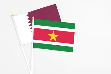 Suriname and Qatar stick flags on white background. High quality fabric, miniature national flag. Peaceful global concept.White floor for copy space.