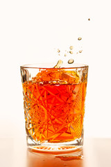 Scotch whiskey elegant glass of whiskey with ice cubes on a white background. Glass of splashing whiskey with ice isolated